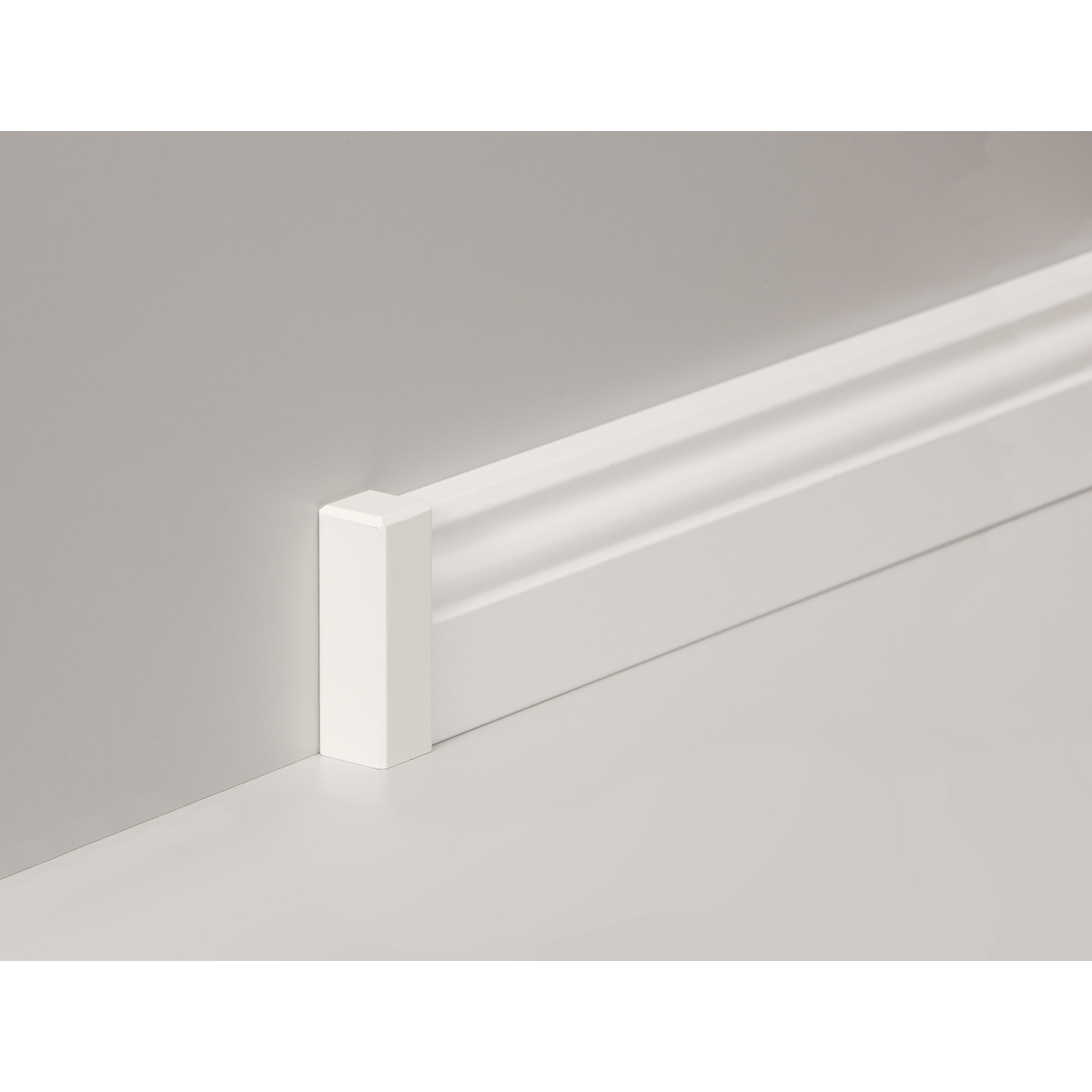 Weiße Sockelleiste aus Holz an einer grauen Wand montiert