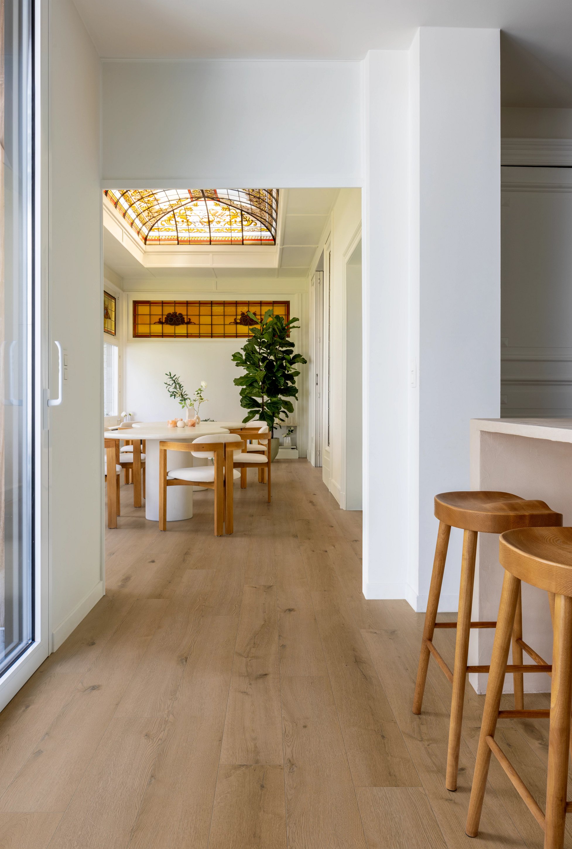 Esszimmer mit Holztisch und -stühlen, Buntglasdecke und Pflanzen