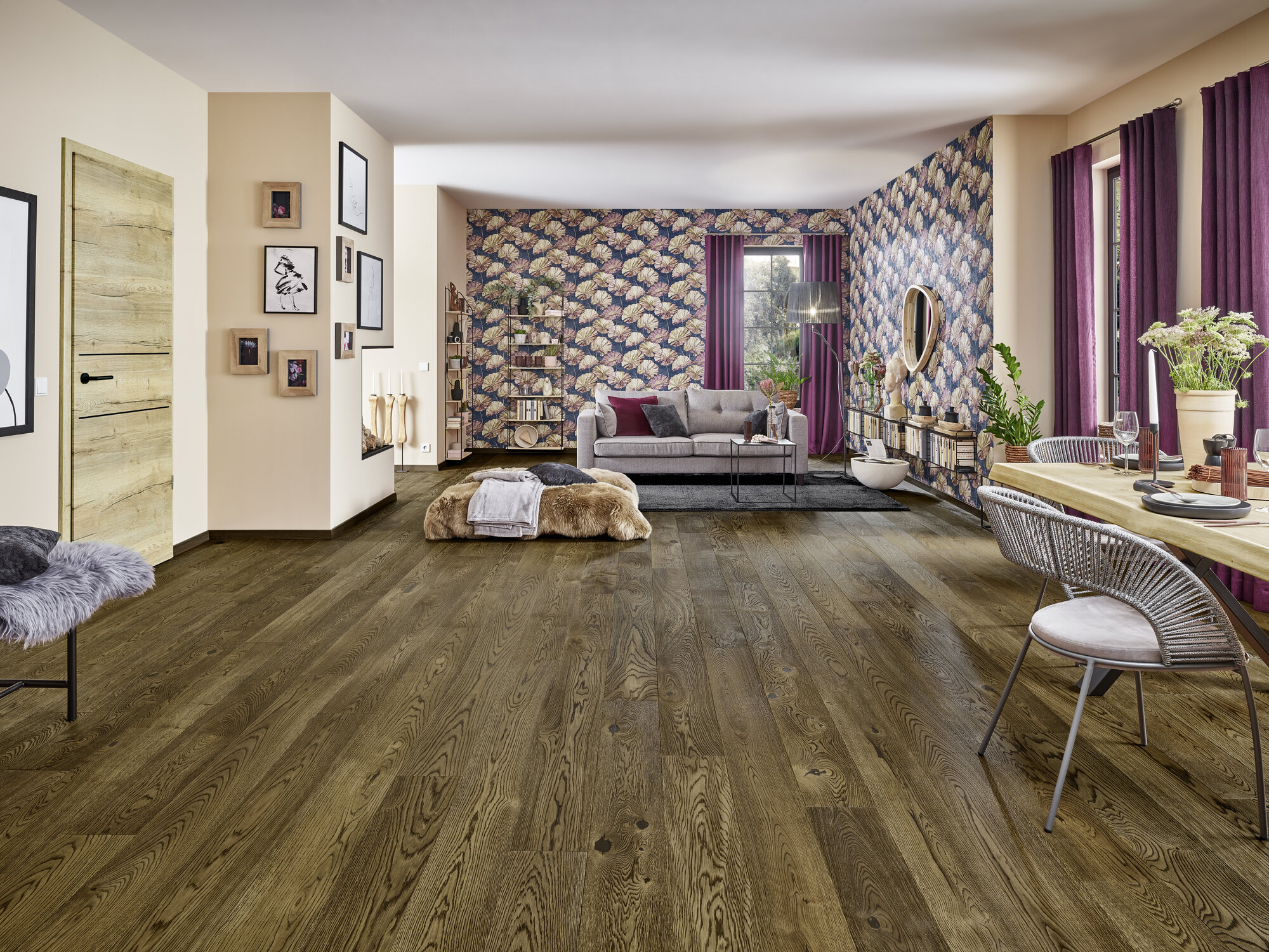 Ein stilvoll eingerichtetes Wohnzimmer mit dunkelbraunem Holzboden, einem gemütlichen Sofa, dekorativer Tapete und Essbereich.