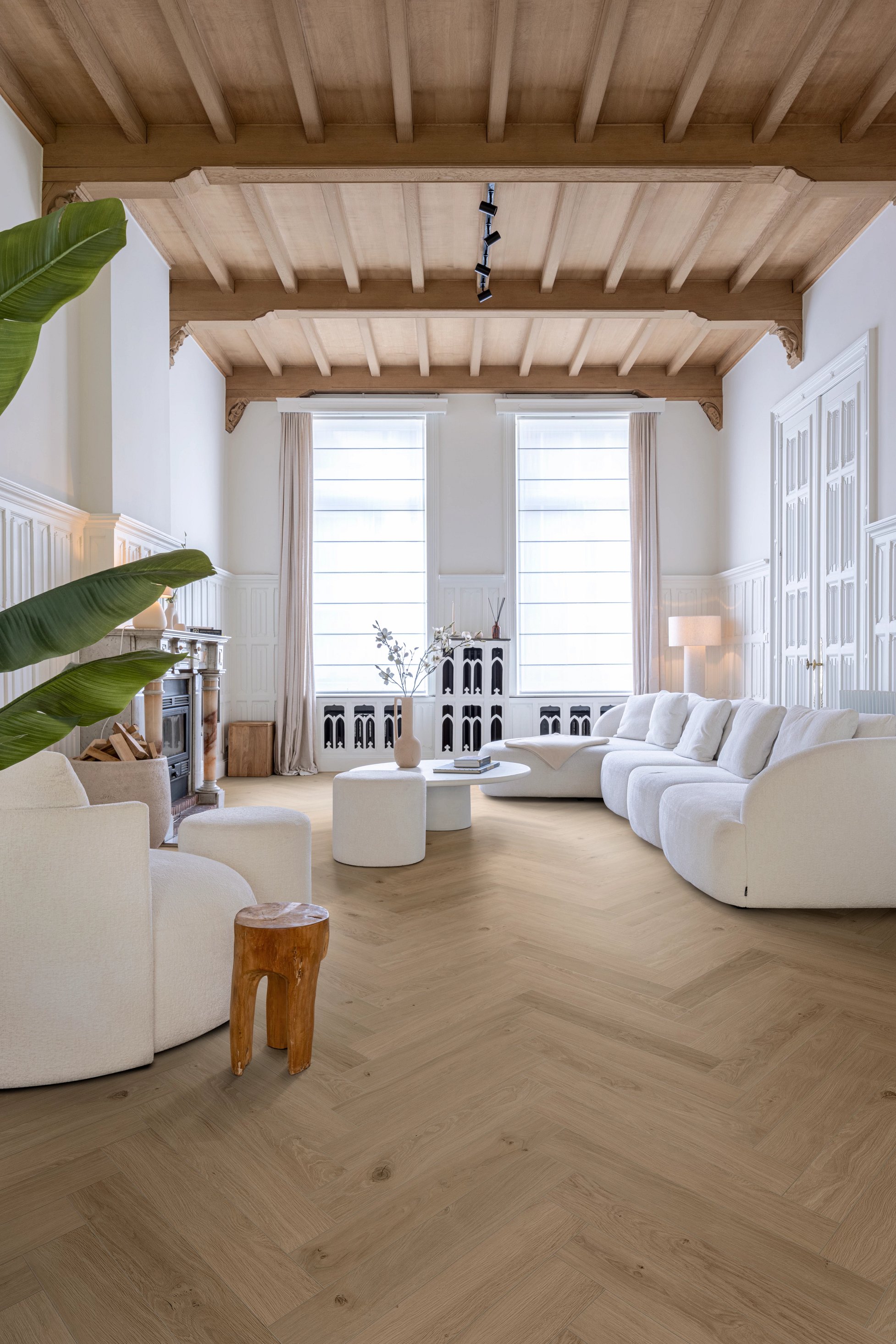 Helles Wohnzimmer mit Holzbalkendecke, weißem Sofa und stilvollem Holzboden