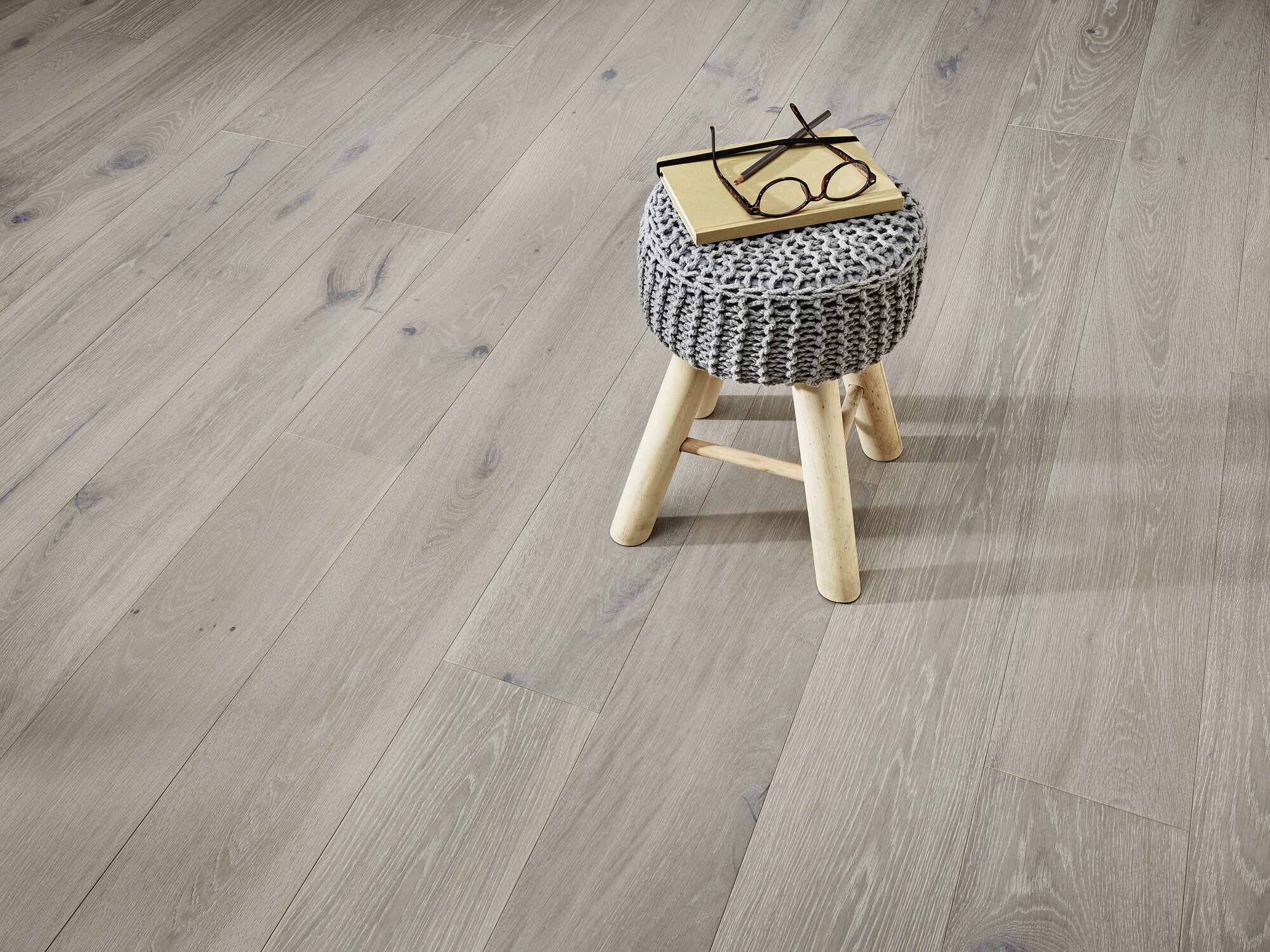 Heller Holzboden mit rustikalem Hocker, Buch und Brille darauf