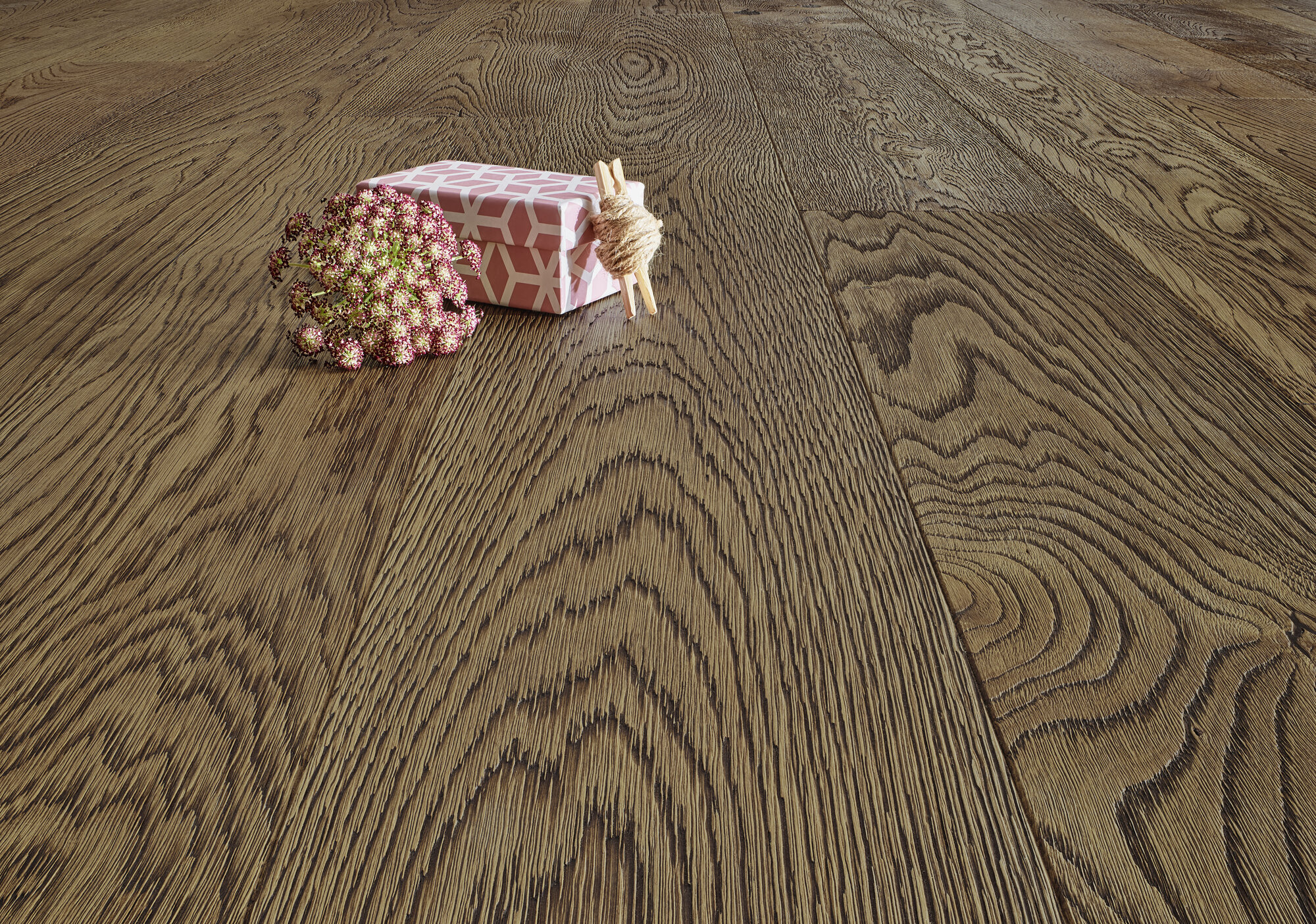 Nahaufnahme eines eleganten Holzbodens mit einer Blume, Geschenkbox und Kordel als Dekoration